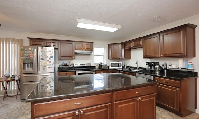 kitchen with a center island, sink, stainless steel appliances, dark stone counters, and a textured ceiling