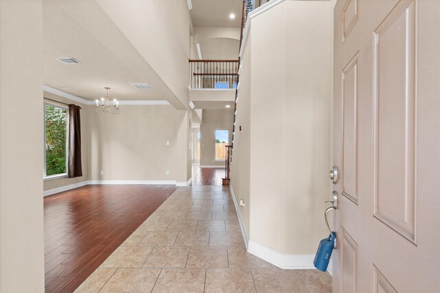 foyer featuring a notable chandelier, crown molding, and light hardwood / wood-style flooring