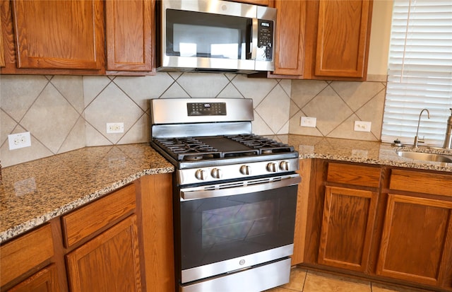 kitchen with sink, light tile patterned flooring, decorative backsplash, and appliances with stainless steel finishes