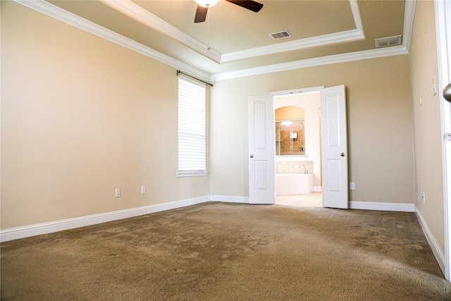 carpeted spare room featuring a raised ceiling, ceiling fan, and ornamental molding