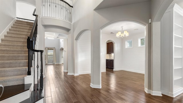 foyer featuring a high ceiling, dark wood-type flooring, and a notable chandelier