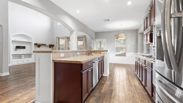 kitchen featuring pendant lighting, dark wood-type flooring, sink, an island with sink, and stainless steel appliances