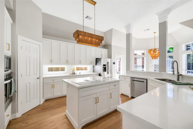 kitchen with pendant lighting, sink, a notable chandelier, light hardwood / wood-style floors, and stainless steel appliances