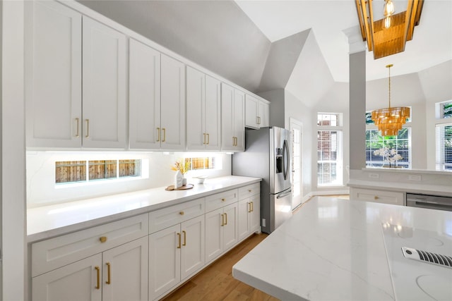 kitchen featuring white cabinetry, stainless steel fridge with ice dispenser, light hardwood / wood-style flooring, pendant lighting, and vaulted ceiling