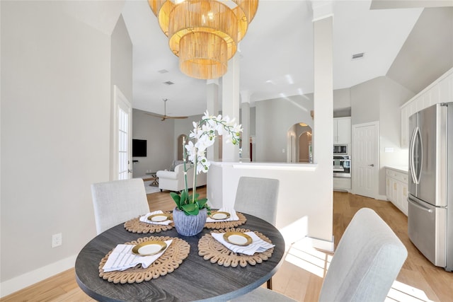 dining space with vaulted ceiling, light hardwood / wood-style flooring, and ceiling fan with notable chandelier