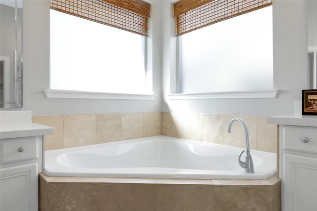 bathroom with vanity and tiled tub