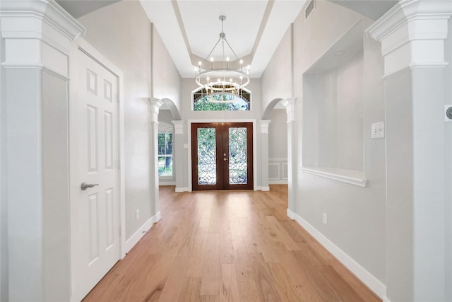 entrance foyer featuring decorative columns, french doors, an inviting chandelier, and light hardwood / wood-style flooring