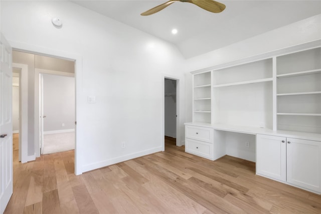 unfurnished office featuring built in desk, light hardwood / wood-style flooring, ceiling fan, and vaulted ceiling