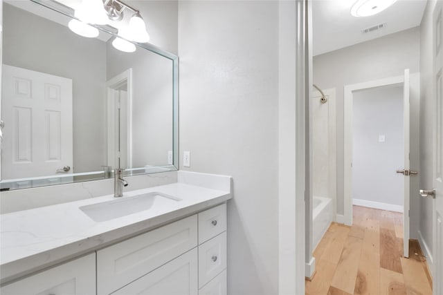 bathroom with bathing tub / shower combination, hardwood / wood-style floors, and vanity