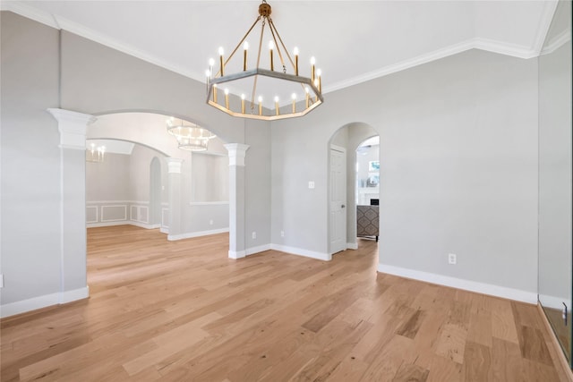 unfurnished dining area with decorative columns, crown molding, and light wood-type flooring