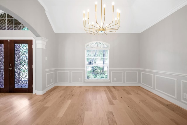 entrance foyer with an inviting chandelier, french doors, light hardwood / wood-style flooring, ornate columns, and ornamental molding