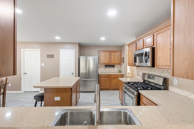 kitchen with light wood-type flooring, backsplash, a breakfast bar, stainless steel appliances, and sink