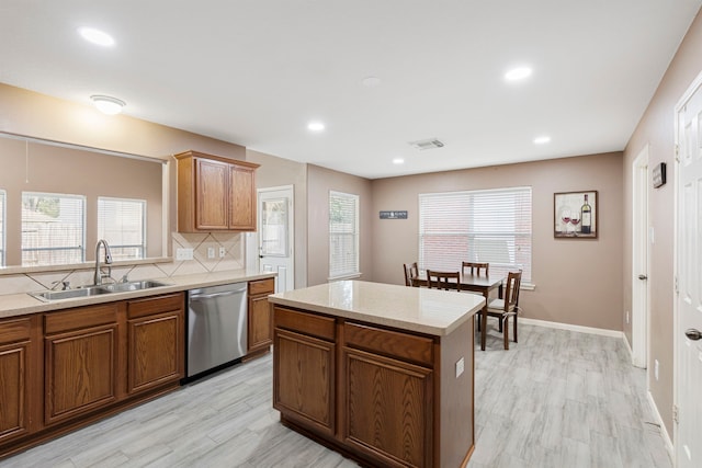 kitchen featuring a wealth of natural light, a center island, stainless steel dishwasher, and sink