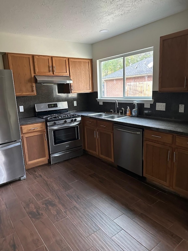 kitchen featuring stainless steel appliances, tasteful backsplash, dark wood-type flooring, and sink