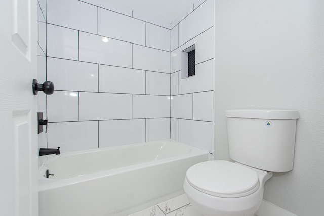 bathroom featuring tiled shower / bath combo and toilet