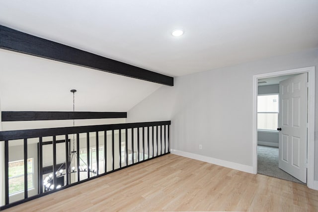 unfurnished room with lofted ceiling with beams and light wood-type flooring