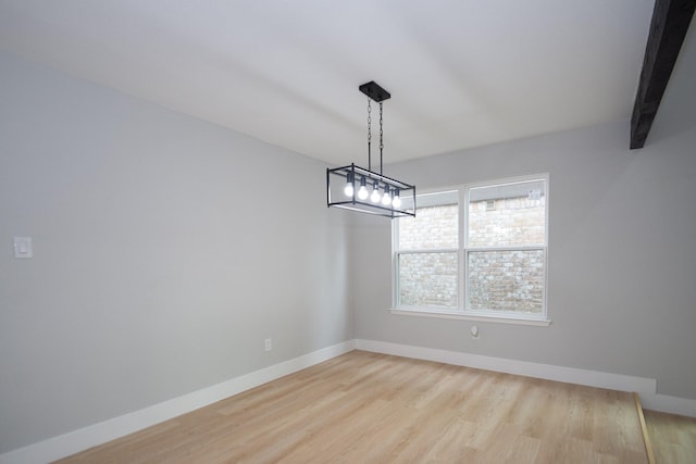 unfurnished dining area with beam ceiling and light wood-type flooring