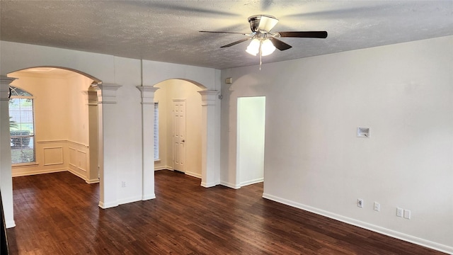 unfurnished room featuring decorative columns, ceiling fan, a textured ceiling, and dark hardwood / wood-style floors