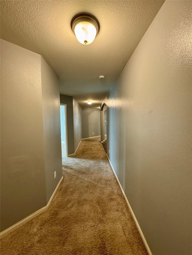 corridor with light carpet and a textured ceiling