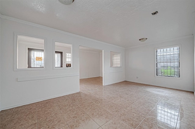 spare room featuring light tile patterned flooring, ornamental molding, and a textured ceiling