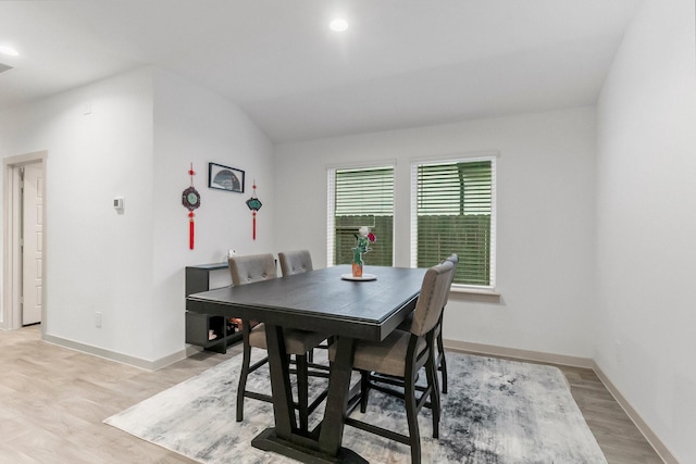 dining area with light hardwood / wood-style floors and vaulted ceiling