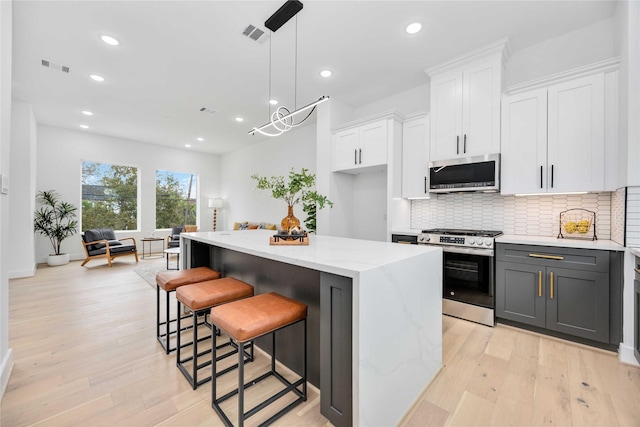 kitchen with pendant lighting, a kitchen island, white cabinetry, and stainless steel appliances