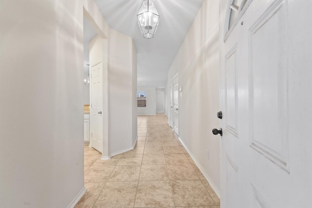 hall with a chandelier and light tile patterned flooring