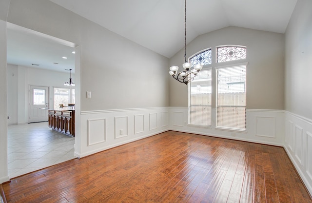 spare room with a chandelier, hardwood / wood-style floors, and lofted ceiling