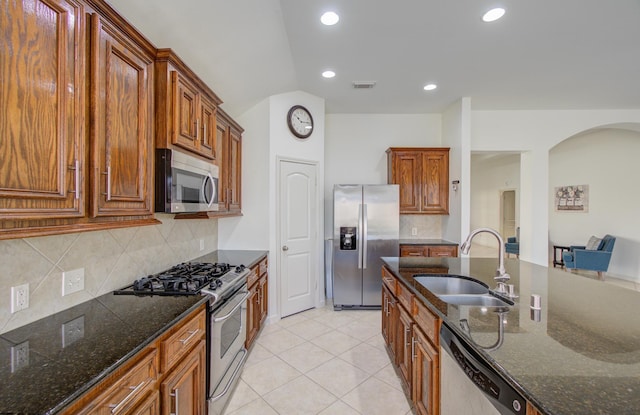 kitchen featuring backsplash, dark stone countertops, sink, and appliances with stainless steel finishes