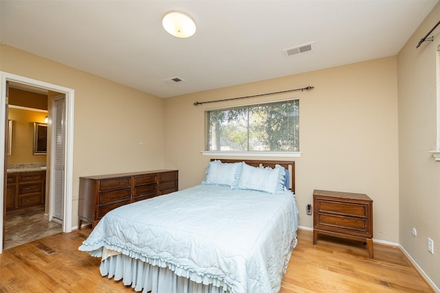 bedroom featuring ensuite bath and light hardwood / wood-style flooring