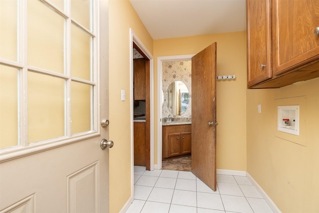 washroom with hookup for a washing machine, light tile patterned flooring, cabinets, and sink