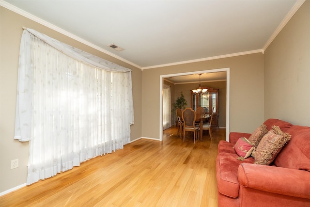 living room featuring wood-type flooring, an inviting chandelier, and crown molding