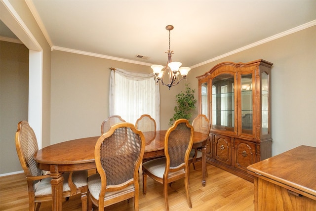 dining area featuring a chandelier, light hardwood / wood-style floors, and crown molding