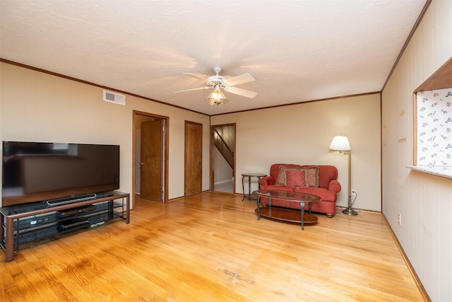 living room with ceiling fan, ornamental molding, a textured ceiling, and hardwood / wood-style flooring