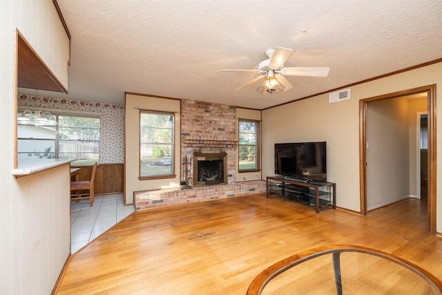 unfurnished living room featuring hardwood / wood-style floors, a textured ceiling, a brick fireplace, and ceiling fan