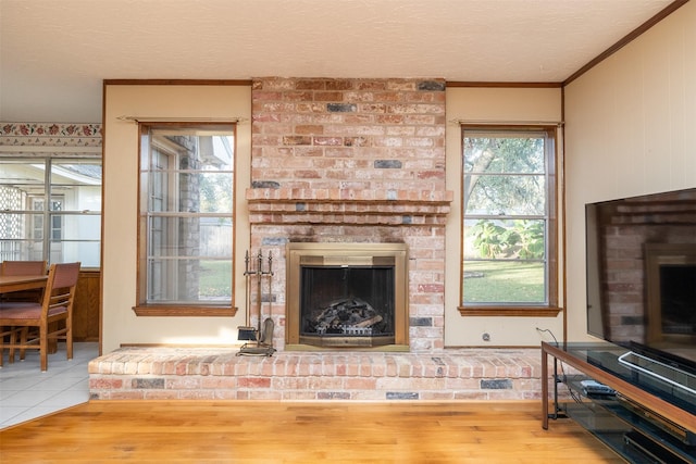 tiled living room with crown molding, a textured ceiling, and a brick fireplace