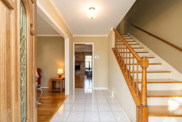 entrance foyer featuring crown molding, a fireplace, and light hardwood / wood-style floors