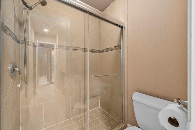 bathroom featuring toilet and a shower with shower door