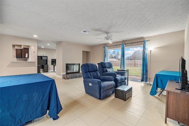 interior space with ceiling fan, a multi sided fireplace, and a textured ceiling