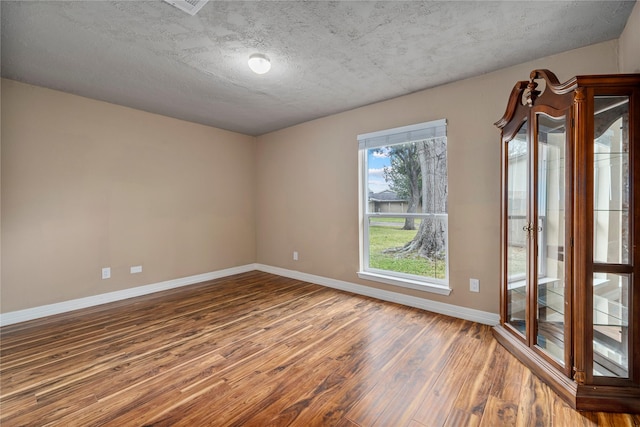 spare room featuring a textured ceiling and hardwood / wood-style flooring