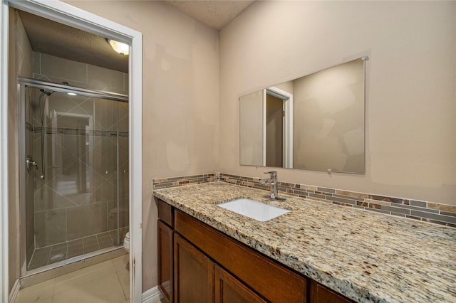 bathroom featuring tile patterned flooring, vanity, a shower with door, and toilet