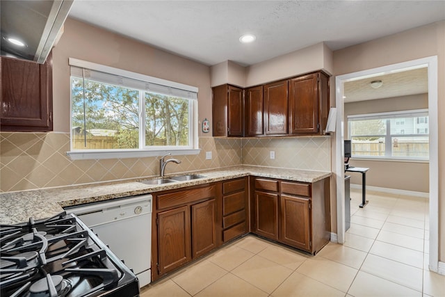 kitchen with stove, white dishwasher, sink, tasteful backsplash, and light stone counters