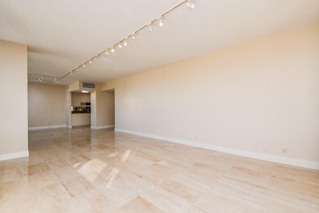 empty room featuring a textured ceiling and track lighting