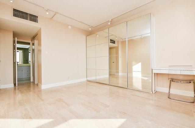 unfurnished bedroom with rail lighting and a closet