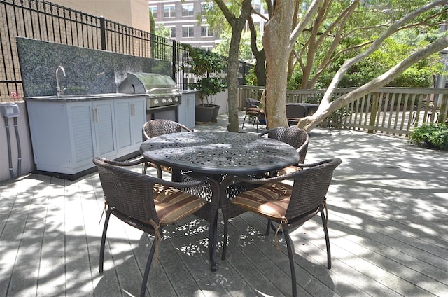 view of patio featuring exterior kitchen, a wooden deck, sink, and grilling area