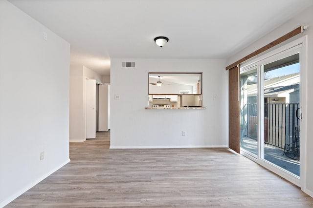 empty room with ceiling fan and light hardwood / wood-style flooring