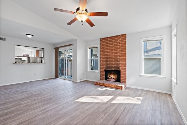 unfurnished living room featuring ceiling fan, light hardwood / wood-style floors, vaulted ceiling, and a brick fireplace