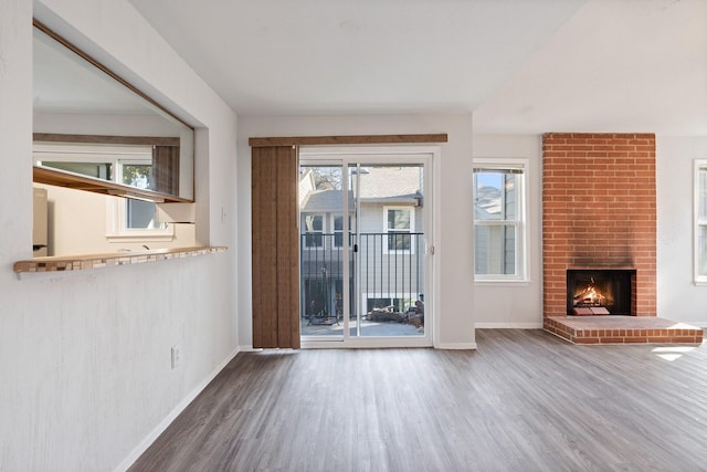 unfurnished living room with a brick fireplace and hardwood / wood-style flooring