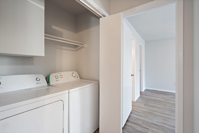 clothes washing area featuring washer and clothes dryer and light hardwood / wood-style flooring