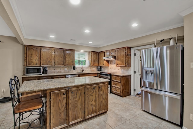 kitchen featuring a center island, crown molding, sink, light stone countertops, and appliances with stainless steel finishes